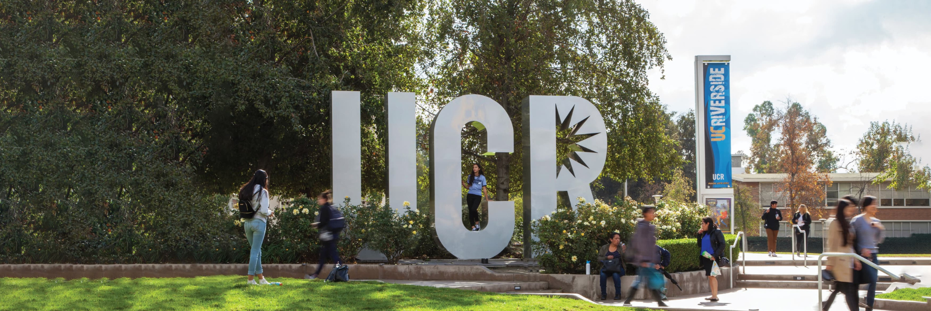 Students on the UCR campus with the UCR sign in focus