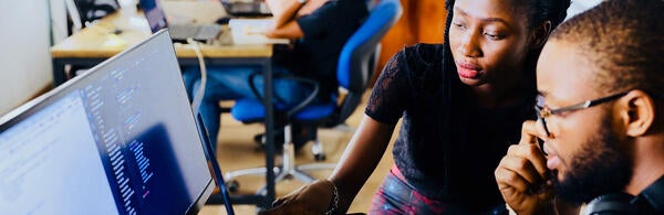 students looking at a computer monitor (c) unsplash