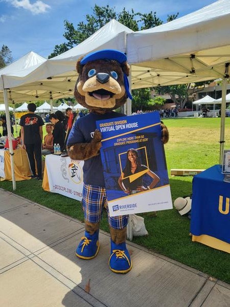 Scotty mascot holding up Grad Open House sign