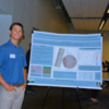 Student poses next to poster at 2024 Symposium