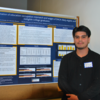 Student poses next to poster at 2024 symposium